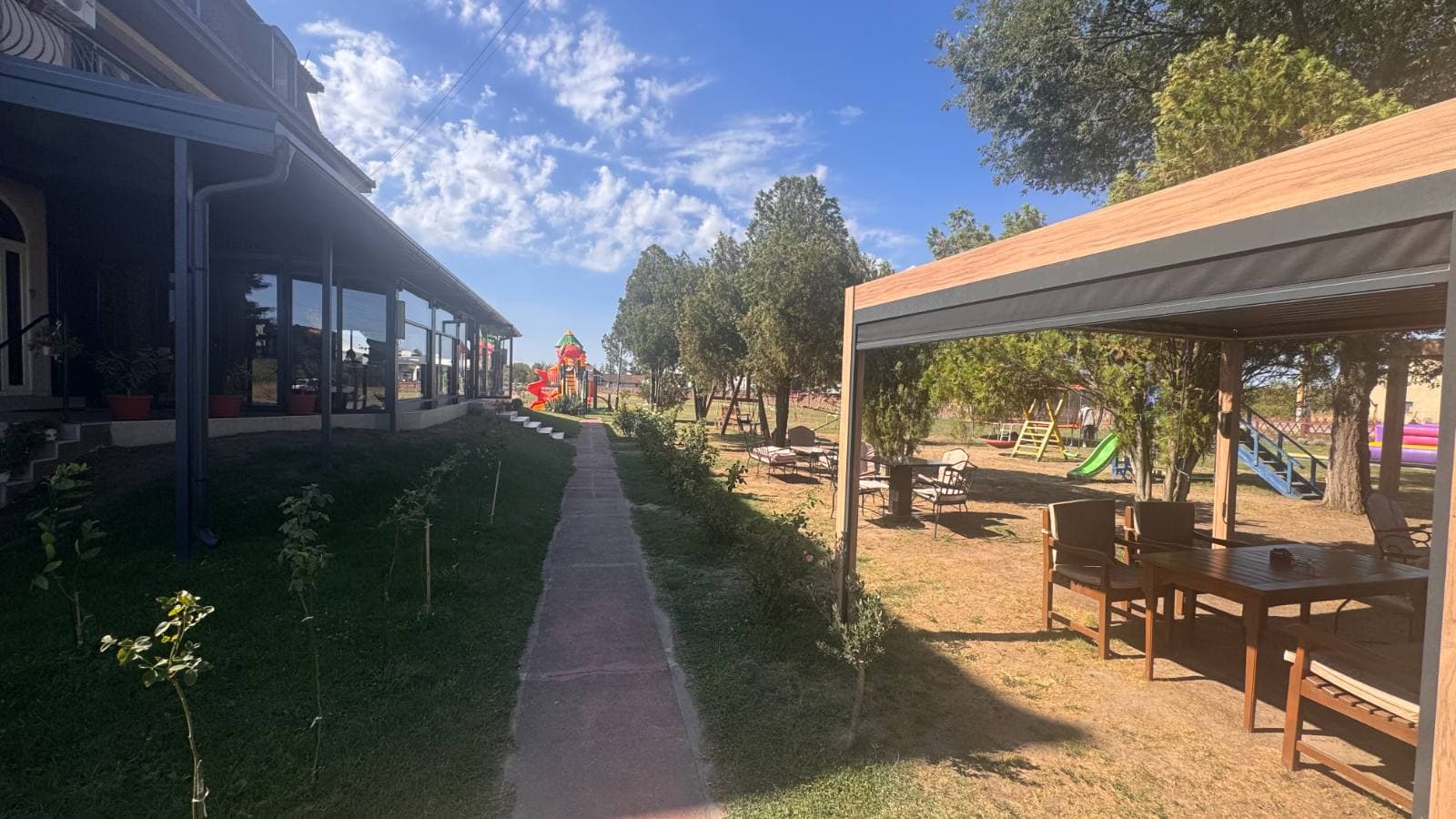 Staza uz staklenu baštu restorana i natkriveni sto u dvorištu